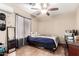 Bedroom featuring wood floors, a ceiling fan, window with curtains, and a dark wood desk at 224 N 236Th Ave, Buckeye, AZ 85396