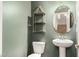 Stylish powder room with a pedestal sink, decorative shelving, and an eye-catching oval mirror at 240 W Juniper Ave # 1146, Gilbert, AZ 85233