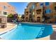 Community swimming pool with lounge chairs and beautiful condo views and sunlit sky at 240 W Juniper Ave # 1146, Gilbert, AZ 85233