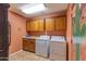 Functional laundry room featuring wood cabinets, modern washer/dryer, and colorful southwest art at 2612 N 161St Ave, Goodyear, AZ 85395