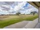 View from covered patio of green backyard that extends to community greenspace with mature trees and lake at 2662 S Springwood S Blvd # 458, Mesa, AZ 85209