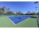 Well-maintained tennis court with a blue playing surface and green surroundings at 3685 N 162Nd Ln, Goodyear, AZ 85395