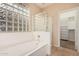 Bright bathroom showcasing a soaking tub and glass-enclosed shower, complemented by a glass block window at 3881 S Marion Way, Chandler, AZ 85286