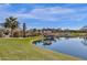 Lush green grass leads to a community pond, showcasing a clock tower, landscaping, and calm waters at 4376 S Santiago Way, Chandler, AZ 85248