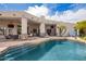 Outdoor living area with in-ground pool, covered seating, and mature landscaping for ultimate relaxation and entertaining at 4438 E Millbrae Ln, Gilbert, AZ 85234