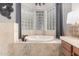 Close-up of the bathroom soaker tub featuring privacy windows, neutral tile, and stylish faucet at 4438 E Millbrae Ln, Gilbert, AZ 85234