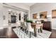 Bright dining room with a wooden table, white upholstered chairs, and view to the foyer at 4438 E Millbrae Ln, Gilbert, AZ 85234