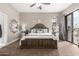 A traditional main bedroom features a wooden bed frame, neutral decor, and a sliding door to the outdoor patio at 4438 E Millbrae Ln, Gilbert, AZ 85234