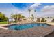 Beautiful in-ground pool with rock waterfall, tropical palms, and brick-paver deck for luxurious outdoor enjoyment at 4438 E Millbrae Ln, Gilbert, AZ 85234