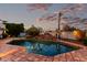 Refreshing pool with rock waterfall feature surrounded by mature landscaping and palm trees under a twilight sky at 4438 E Millbrae Ln, Gilbert, AZ 85234