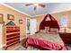 Comfortable bedroom with red accents, ceiling fan, chest of drawers, and wooden laminate flooring at 4444 W Chama Dr, Glendale, AZ 85310