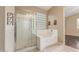 A well-lit bathroom boasts a glass-enclosed shower and a soaking tub beneath a bright glass block window at 4806 E Thunderbird Dr, Chandler, AZ 85249