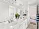 Bright bathroom featuring double sinks, white cabinetry, modern fixtures, and view into an adjacent bedroom at 6212 E Lonesome Trl, Cave Creek, AZ 85331