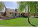 Lush backyard with a large, well-kept lawn, mature trees, and view of the home's exterior at 6228 W Caribbean Ln, Glendale, AZ 85306