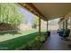 Landscaped backyard with covered patio, lush grass, trees, and planters creating an inviting outdoor space at 6228 W Caribbean Ln, Glendale, AZ 85306