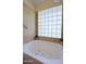 Soaking tub with glass block window and neutral tile, offering natural light and a modern aesthetic at 6228 W Caribbean Ln, Glendale, AZ 85306