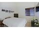 Bedroom with a white bed, neutral walls, and an accent of black and white artwork for a minimalist style at 6228 W Caribbean Ln, Glendale, AZ 85306