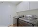 Convenient laundry room with modern washer and dryer units, storage cabinets, and a clean, functional design at 6228 W Caribbean Ln, Glendale, AZ 85306