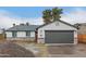 Charming exterior view with a gray two-car garage door, stone accents, and ample driveway space at 6812 S 41St Pl, Phoenix, AZ 85042