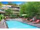 A pool surrounded by lounge seating, trees, and a multistory building under blue skies at 7121 E Rancho Vista Dr # 3001, Scottsdale, AZ 85251