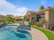 Backyard oasis featuring a pool with waterfall, outdoor kitchen, covered patio, and meticulously landscaped greenery at 10829 E Volterra Ct, Scottsdale, AZ 85262