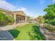 Expansive backyard with lush landscaping, artificial turf, and a sparkling pool with an umbrella at 10829 E Volterra Ct, Scottsdale, AZ 85262