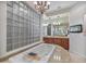 Bathroom featuring a bathtub with granite surround, chandelier, dual vanities and block-glass window at 10829 E Volterra Ct, Scottsdale, AZ 85262