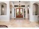 Bright foyer with tiled flooring, arched doorways, and a wooden double door entry at 10829 E Volterra Ct, Scottsdale, AZ 85262