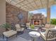 Outdoor patio features a stone fireplace, covered seating area, and lush landscaping at 10829 E Volterra Ct, Scottsdale, AZ 85262