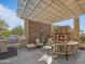 A covered outdoor patio with fireplace, stone wall, grill, desert views and plenty of seating at 10829 E Volterra Ct, Scottsdale, AZ 85262