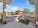 Outdoor kitchen with stainless steel grill, granite counters, mini-refrigerator and desert views at 10829 E Volterra Ct, Scottsdale, AZ 85262