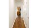 Hallway with wood floors, white walls, and view of a bedroom with dresser and mirror at 13216 S 175 Dr, Goodyear, AZ 85338