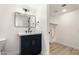 Contemporary bathroom with navy-blue vanity, modern mirror, and a glimpse into the adjacent room at 13244 N 54Th Dr, Glendale, AZ 85304