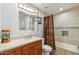 Well-lit bathroom with vanity, updated fixtures, and tiled shower and tub with a decorative curtain at 13942 W Summerstar Dr, Sun City West, AZ 85375