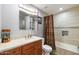 Well-lit bathroom with vanity, updated fixtures, and tiled shower and tub with a decorative curtain at 13942 W Summerstar Dr, Sun City West, AZ 85375