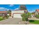 Attached two-car garage with a long driveway, desert landscaping, and a well-maintained lawn at 13942 W Summerstar Dr, Sun City West, AZ 85375