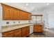 Classic kitchen featuring granite countertops, wood cabinetry, sink beneath window, and tile flooring at 13942 W Summerstar Dr, Sun City West, AZ 85375