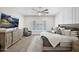 Spacious bedroom with wood-style tile flooring, ceiling fan, TV, and cozy gray armchair at 1547 E Crescent Way, Gilbert, AZ 85298