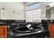 A soaking tub sits between two cabinets with granite countertops, complemented by a glass block window at 16253 W Windcrest Dr, Surprise, AZ 85374