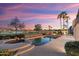 Relaxing backyard with a pool, spa, and palm trees under a colorful sky at sunset at 16253 W Windcrest Dr, Surprise, AZ 85374