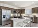 Spacious kitchen with stainless steel appliances, an island with bar seating, and dark wood cabinets at 17742 W Brown St, Waddell, AZ 85355