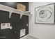 Well-organized laundry room with shelving, dark walls, and contemporary artwork, providing practical style at 17742 W Brown St, Waddell, AZ 85355