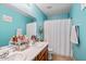 Bright bathroom with double sinks, wood cabinets, and a shower/tub combination with a white curtain at 25067 W Dove Trl, Buckeye, AZ 85326