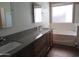 Bathroom featuring a double vanity, quartz countertops, a soaking tub, and a bright window at 2830 W Grenadine Rd, Phoenix, AZ 85041