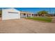 View of a white home with an attached garage, covered porch, manicured lawn, and a concrete driveway at 3028 E Highland Ave, Phoenix, AZ 85016