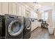 Updated laundry room with front loading washer and dryer, desk, and custom cabinetry at 36518 N Crucillo Dr, Queen Creek, AZ 85140