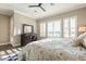 Bright main bedroom with windows offering golf course views, ceiling fan, and dark wood furnishings at 36518 N Crucillo Dr, Queen Creek, AZ 85140