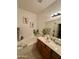 Well-lit bathroom featuring bathtub, cherry-wood vanity, decorative plants, and modern fixtures at 36610 W Picasso St, Maricopa, AZ 85138