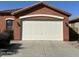 View of the two-car garage featuring a white door and exterior wall mounted sconces at 36610 W Picasso St, Maricopa, AZ 85138