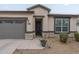 Home exterior featuring well-manicured landscaping, neutral stucco, grey garage door, and a decorative flower pot at 38101 W Santa Maria St, Maricopa, AZ 85138